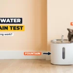 Grey tabby cat wearing a collar with an RFID tag, drinking from a white smart water fountain against a peach wall